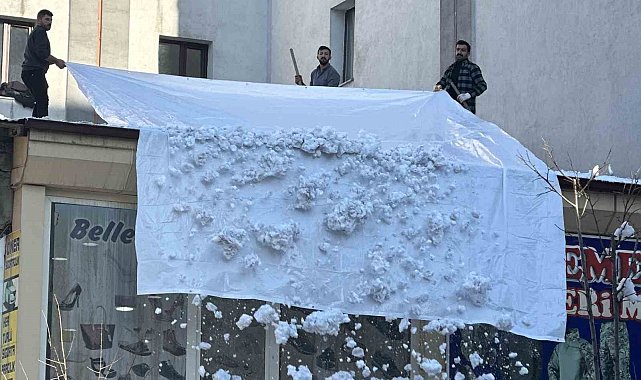 Vatandaşlar çatıdaki kar kütlelerini brandayla indirdi